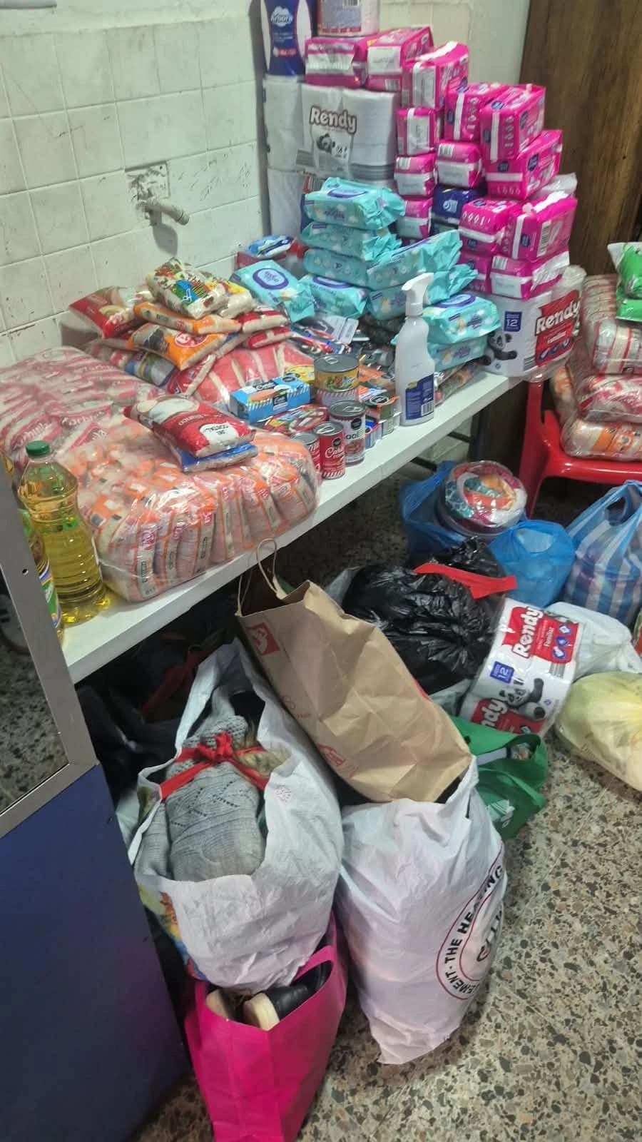 Mesa con arroz, pastas, enlatados y elementos de aseo ya clasificados, y bolsas de ropa y calzado guardadas debajo
